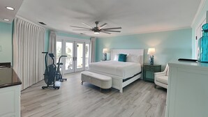 Ruime slaapkamer met een groot bed, een plafondventilator en uitzicht op de omgeving door een schuifdeur.