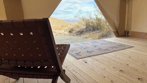 A tent with a wooden floor and a single brown chair.
