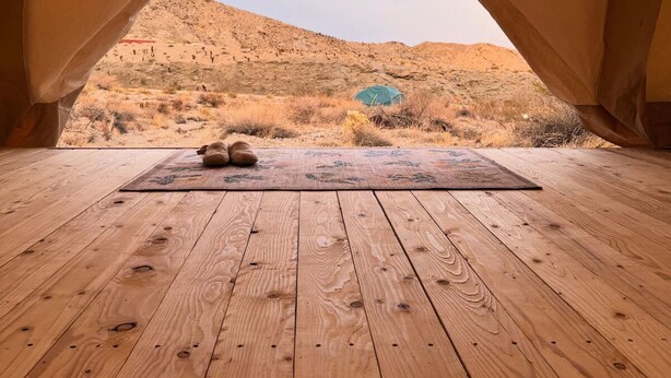A tent with a wooden floor and a view of a desert landscape.