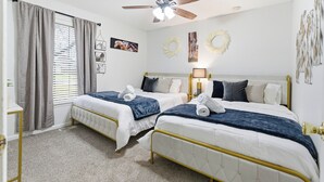 A bedroom with two beds, a ceiling fan, and a window with curtains. - The Bourbon Trail Bungalow Ping Pong/Foosball/Bar/Firepit (Mount Washington)