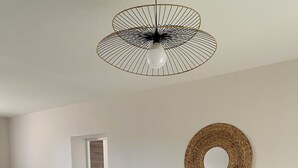 A modern dining area with a wooden table, chairs, and a unique ceiling light fixture.