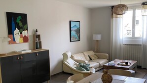 A modern living room with a dining table, sofa, and a painting on the wall.