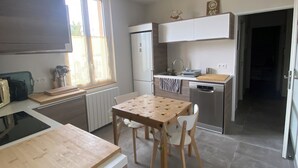 A modern kitchen with a dining table, chairs, and a refrigerator.