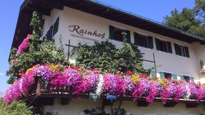 A building with a sign reading "Rainhol FRÜHSTÜCKSPENSION" and a balcony with colorful flowers. - Pension Rainhof (Kitzbuhel)