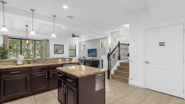 A spacious kitchen with dark wood cabinets, a granite countertop, and pendant lighting. - Dluxx Tranquil 4BR Cozy Home w Full Kitchen 8115 (Davenport)