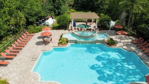 A large outdoor swimming pool with lounge chairs and umbrellas, surrounded by greenery. - Dluxx Tranquil 4BR Cozy Home w Full Kitchen 8115 (Davenport)