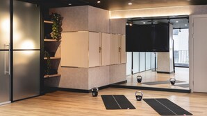 Ein moderner Fitnessraum mit Holzböden, Trainingsmatten und Kettlebells.