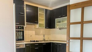A modern kitchen with black cabinets, a glass dining table, and a wooden floor.