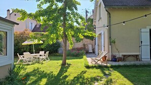 Ein Innenhof mit Tisch und Stühlen, einem kleinen Baum und einer Lichterkette.
