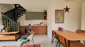 Eine moderne Küche mit Holztisch und -stühlen, einem Essbereich und einer Treppe mit schwarzen Geländern.
