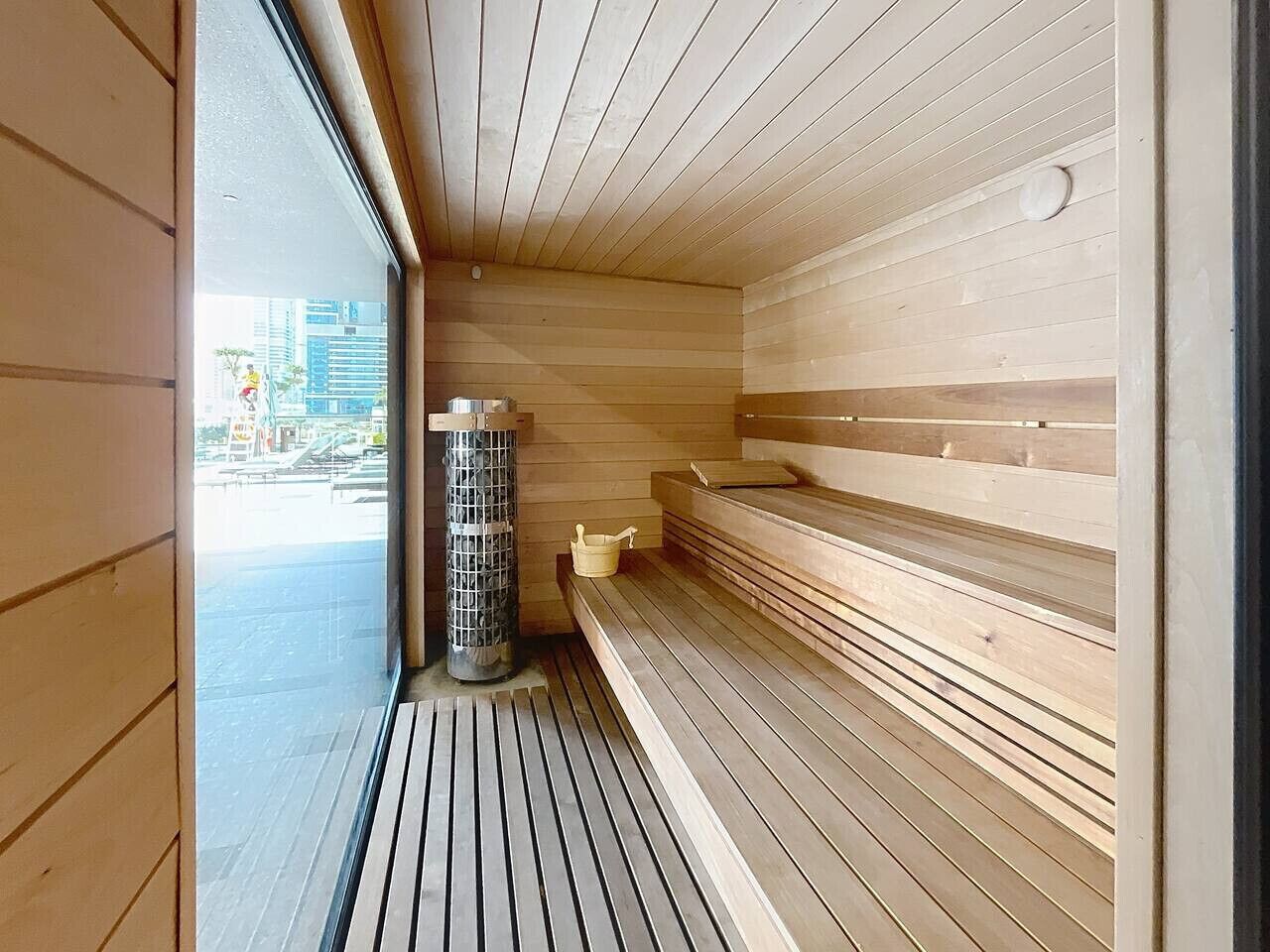 Un sauna avec des bancs en bois et une porte en verre.
