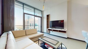 Een moderne woonkamer met een bank, een salontafel en een aan de muur bevestigde televisie.