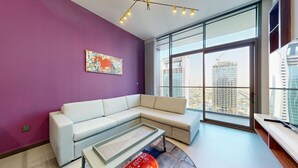 Een moderne woonkamer met een witte modulaire bank, een glazen salontafel en een groot raam met uitzicht op de stad.