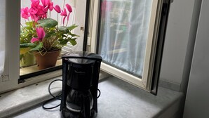 A coffee maker on a kitchen counter near a window with a view of a balcony with potted plants. - Posillipo - panoramic apartment in the heart of the sea of Naples (Napoli)