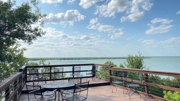 A wooden deck with metal chairs and tables overlooking a body of water. - Lakefront fun for 14+pets w/game room deck sunsets (Whitney)