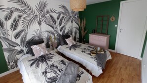 Une chambre avec deux lits, un mur vert et un plancher en bois.
