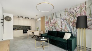 Ein modernes Wohnzimmer mit einem grünen Sofa, einem runden Couchtisch und einer großen Blumenwand.