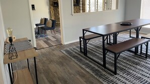 Een moderne eethoek met een lange tafel en banken, een accentmuur van steen en een plafondventilator.