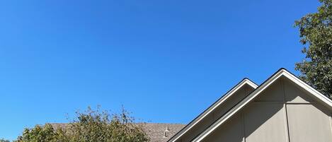 A single-story house with a stone facade, a garage, and a clear blue sky.