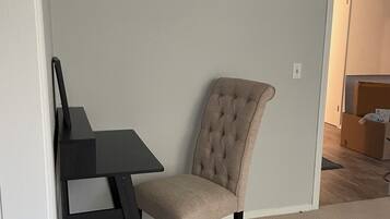 A room with a dining table and a tufted chair, carpeted floor, and a door leading to another room.
