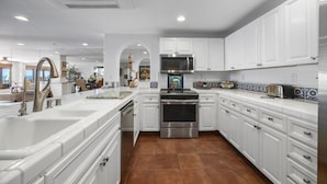 A modern kitchen with white cabinetry, stainless steel appliances, and a large island with a sink. - H1864: Remodeled 2Br villa, AC, 4-seat cart, OCEAN VIEWS, BBQ (Avalon)