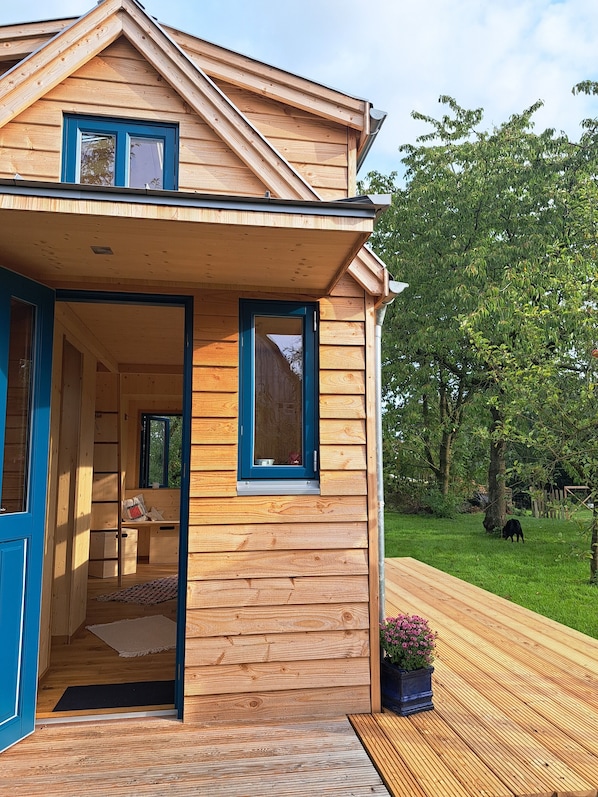 A wooden house with a balcony, a door, and a window.