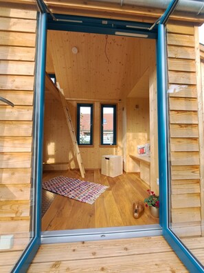 A wooden interior with a ladder, a small white table, and a colorful rug.