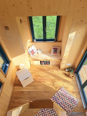 A wooden interior with a bench, a small table, and a window with a view of greenery.