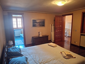 Ein Schlafzimmer mit Bett, Kommode, einem Bild und einer Tür zu einem anderen Raum.