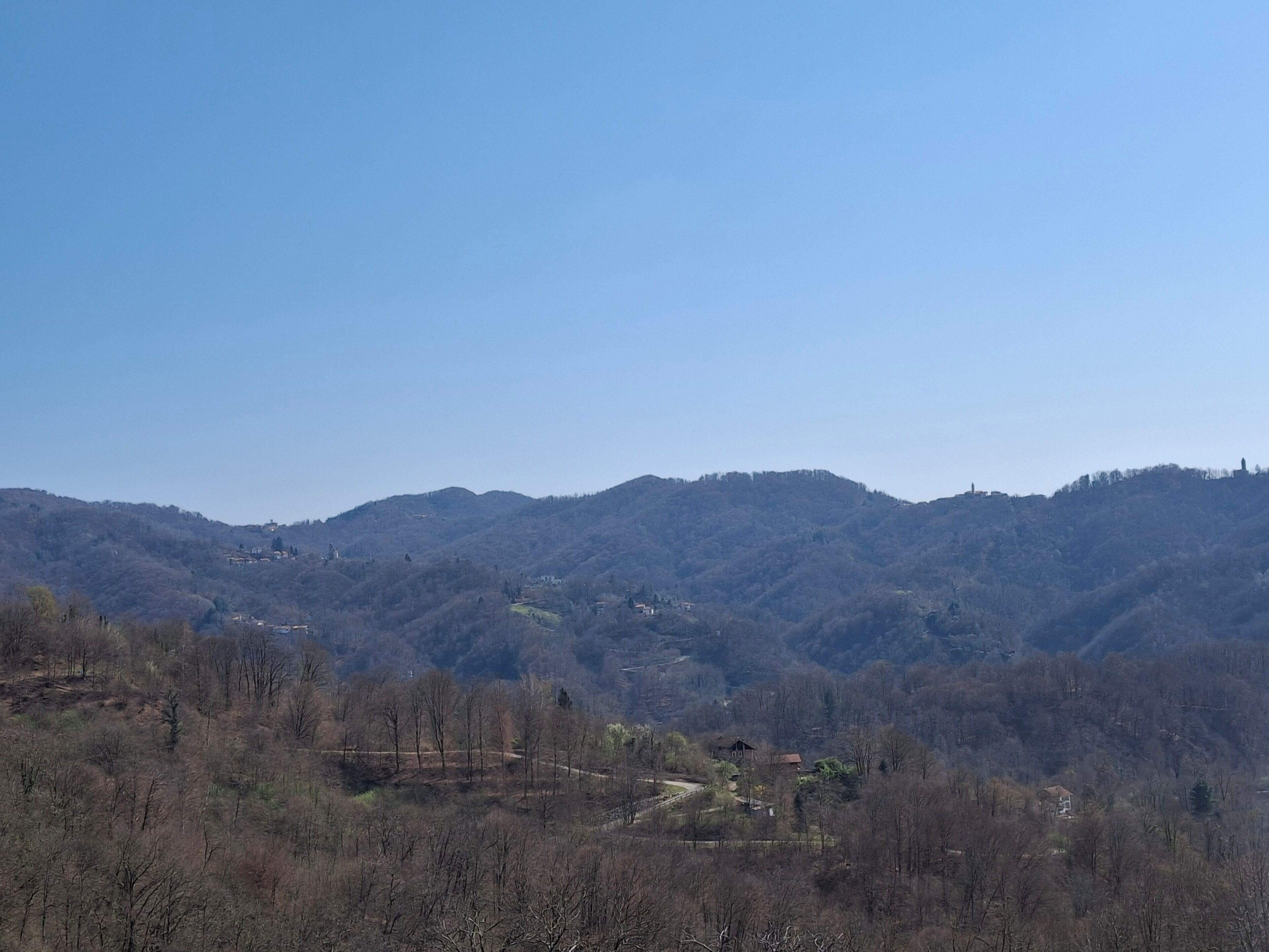 A mountainous landscape with sparse trees and a few buildings.