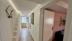 Ein Flur mit Treppe, einer Tür und einem an der Wand befestigten Hirschgeweih.