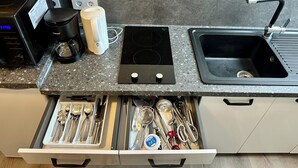 Eine Küche mit Kaffeemaschine, Wasserkocher, Herd, Spüle und einer Schublade mit Besteck.