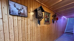 Eine Holzwand mit einem gerahmten Bild von einem Reh, einer Kuckucksuhr und einem Blumenbild.