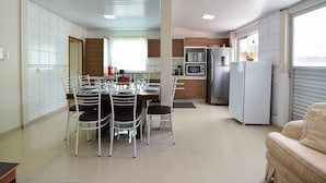 Une cuisine moderne avec un coin repas, comprenant un îlot central, des appareils électroménagers intégrés et une grande fenêtre.