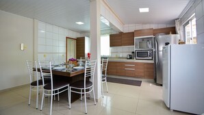 Une cuisine moderne avec des meubles blancs, une table à manger avec des chaises et un réfrigérateur.