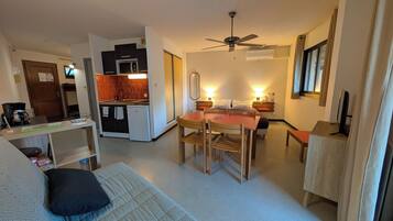 Een knus woongedeelte met een kitchenette, een eethoek en een bed.