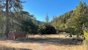 A rural landscape with a red barn, a dirt path, and dense trees. - Private 1-bedroom 1-bathroom guest suite in the forested area of Trinity County. (Big Bar)
