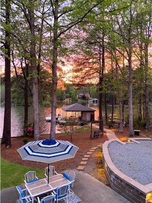 Une terrasse au bord du lac, avec une table et des chaises, entourée d’arbres et agrémentée d’un belvédère.