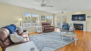 A spacious living room with a fireplace, leather sofas, a coffee table, and a flat-screen TV.