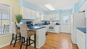 A modern kitchen with white cabinets, a central island, and a blue backsplash.