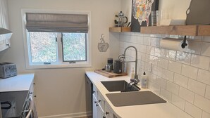 A modern kitchen with a built-in oven, a sink, and a window with a view of trees. - 2 Bedroom Condo -Views of West Point and Hudson River, steps from Metro North! (Garrison)