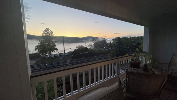 A balcony with a view of a lake, a house, and a bridge. - 2 Bedroom Condo -Views of West Point and Hudson River, steps from Metro North! (Garrison)