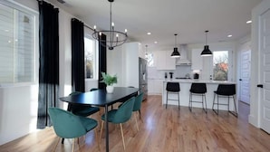 A modern kitchen with a dining area, featuring a large island, pendant lights, and a potted plant. - SIDE BY SIDE HOMES - 8 BEDROOMS- 2 HOT TUBS (Nashville)