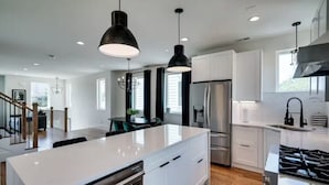 A modern kitchen with white cabinetry, stainless steel appliances, and pendant lighting. - SIDE BY SIDE HOMES - 8 BEDROOMS- 2 HOT TUBS (Nashville)