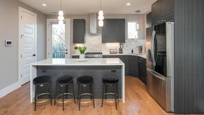 A modern kitchen with a central island, bar stools, stainless steel appliances, and dark cabinetry. - SIDE BY SIDE HOMES - 8 BEDROOMS- 2 HOT TUBS (Nashville)