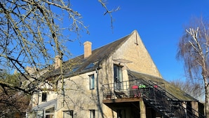 Un edificio in pietra con un balcone, una scalinata e un piccolo giardino.