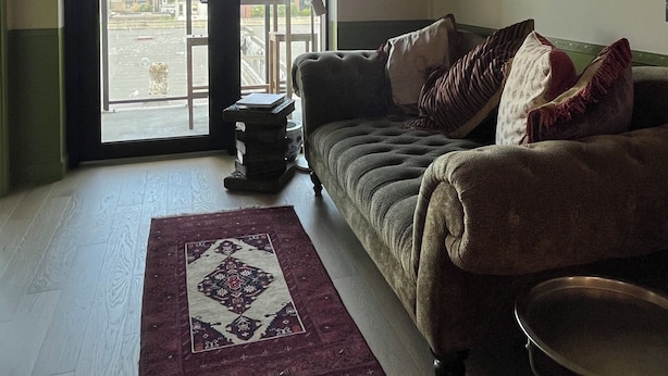 A living room with a sofa, a coffee table, a rug, and a ceiling fan.