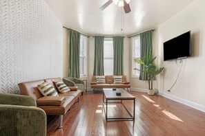 Un salon comprenant un canapé, un fauteuil, une table basse et un téléviseur fixé au mur.