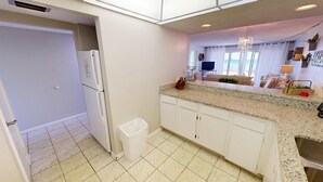 A kitchen with white cabinets, a granite countertop, and a stainless steel sink. - Stunning 1st floor 2 bed w/beach service (Miramar Beach)