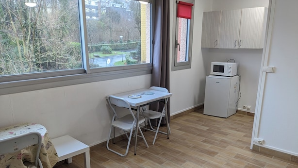 A small, tidy room with a foldable table and chairs, a microwave, and a cabinet. - Quiet apartment - furnished (Rouen)